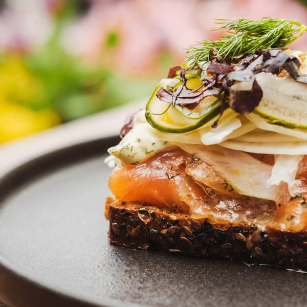 Nem's Japandi Bistro's salmon toast with dill, zucchini, and creamy sauce on dark bread.