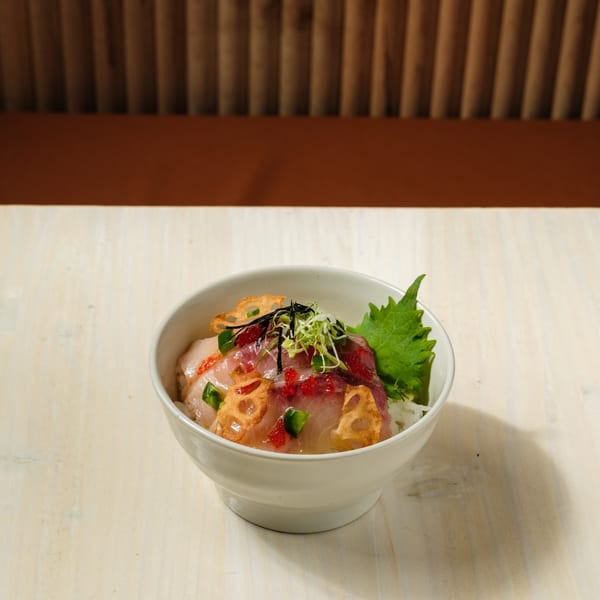 A white bowl of Nem's Japandi Bistro's chirashi sushi with fish, roe, and lotus root.