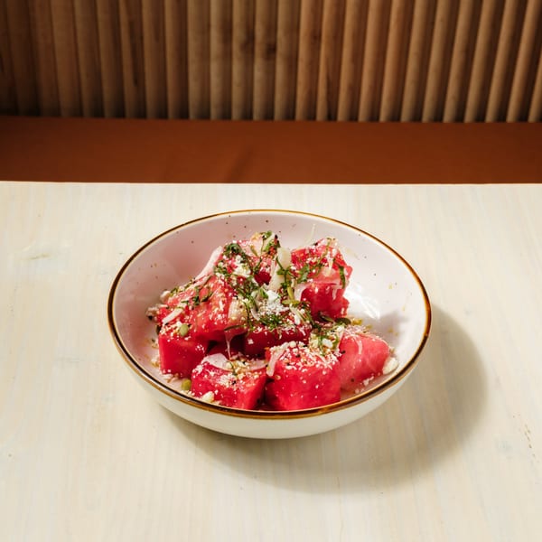 Nem's Japandi Bistro's watermelon salad with feta, herbs, and seeds in a white bowl.