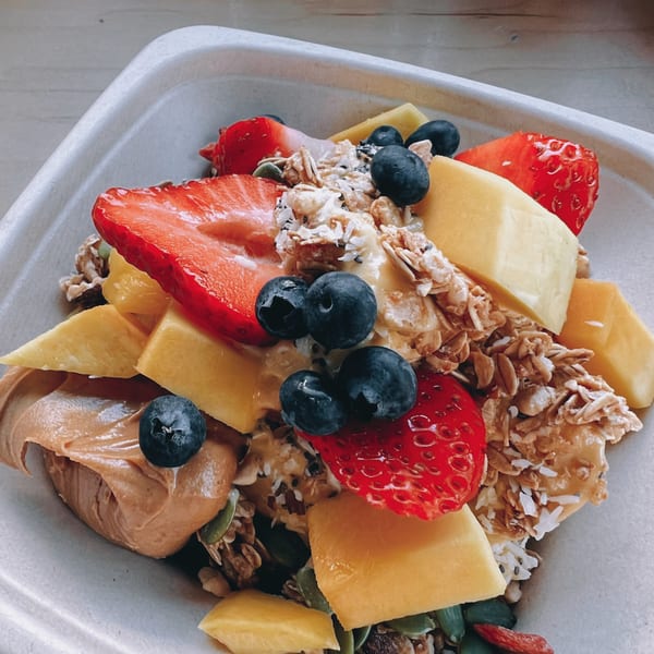 A colorful Nem's Japandi Bistro acai bowl with strawberries, blueberries, mango, granola, and peanut butter.