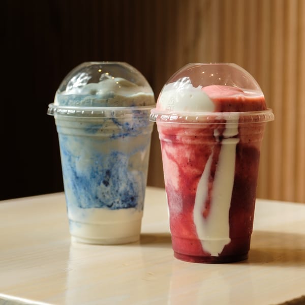 Two Nem's Japandi Bistro smoothies, one blue and one red, with white swirls in clear cups.