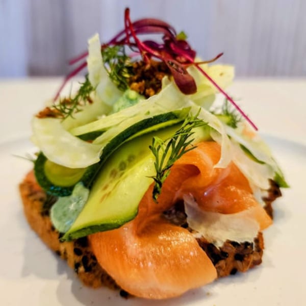 Nem's Japandi Bistro's open-faced sandwich with salmon, cucumber, and greens on dark bread.
