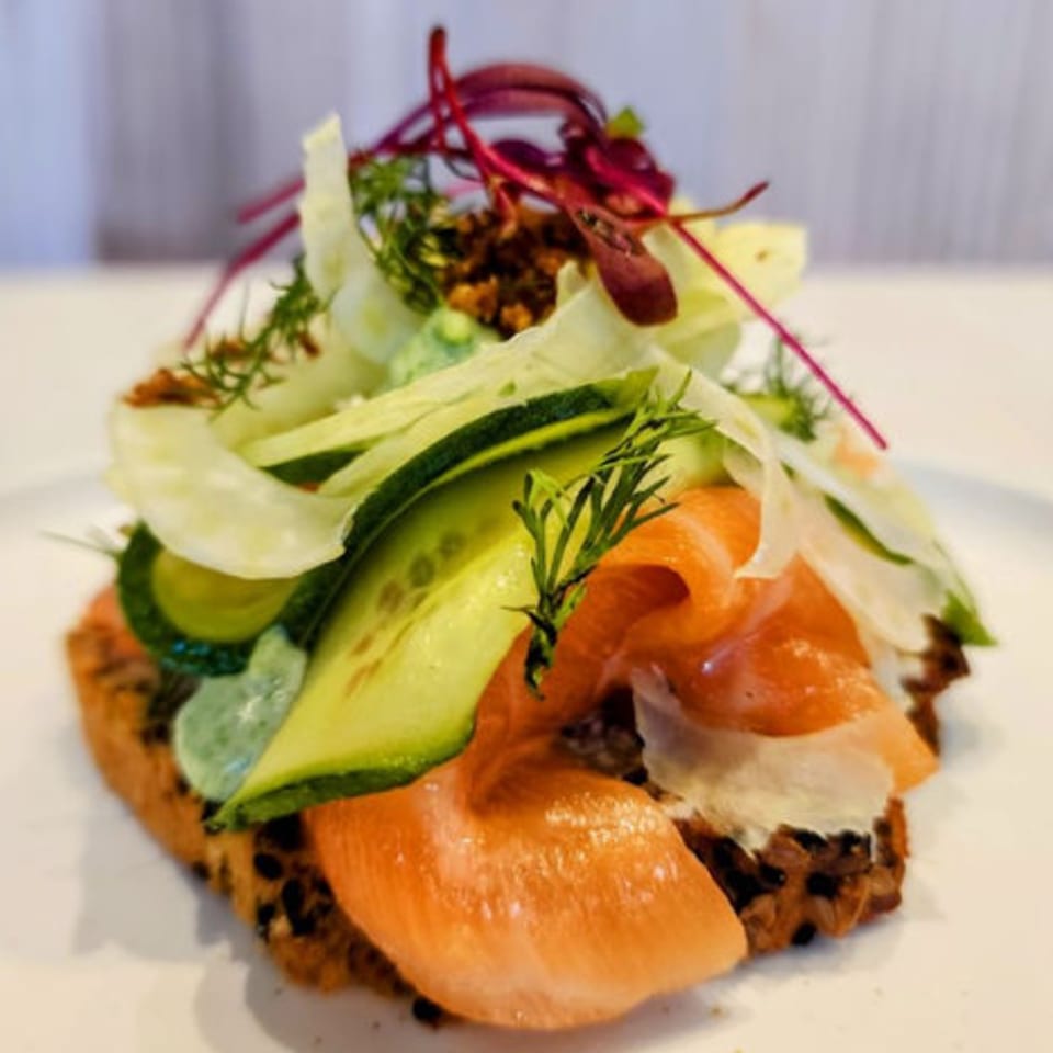 Nem's Japandi Bistro's open-faced sandwich with salmon, cucumber, and greens on dark bread.